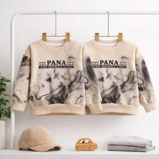 نمایش دو عدد بلوز تک دورس پسرانه کرم رنگ طرح ماربل مدل PANA آویزان شده روی رگال لباس با دکور کلاه مخمل و ماشین چوبی.